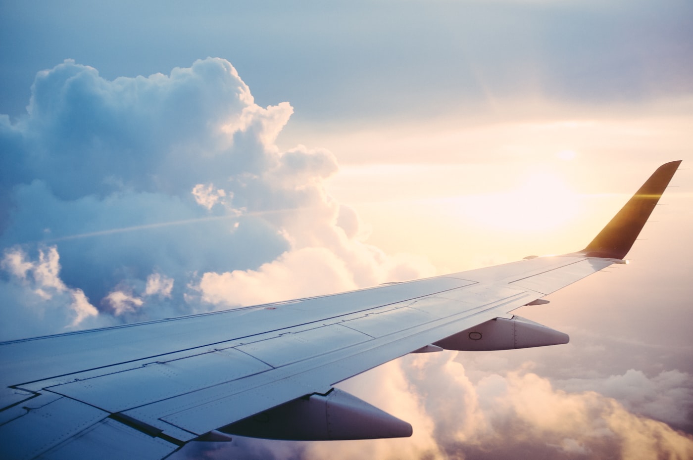Airplane wing above clouds for planning the first hotel night after a long flight