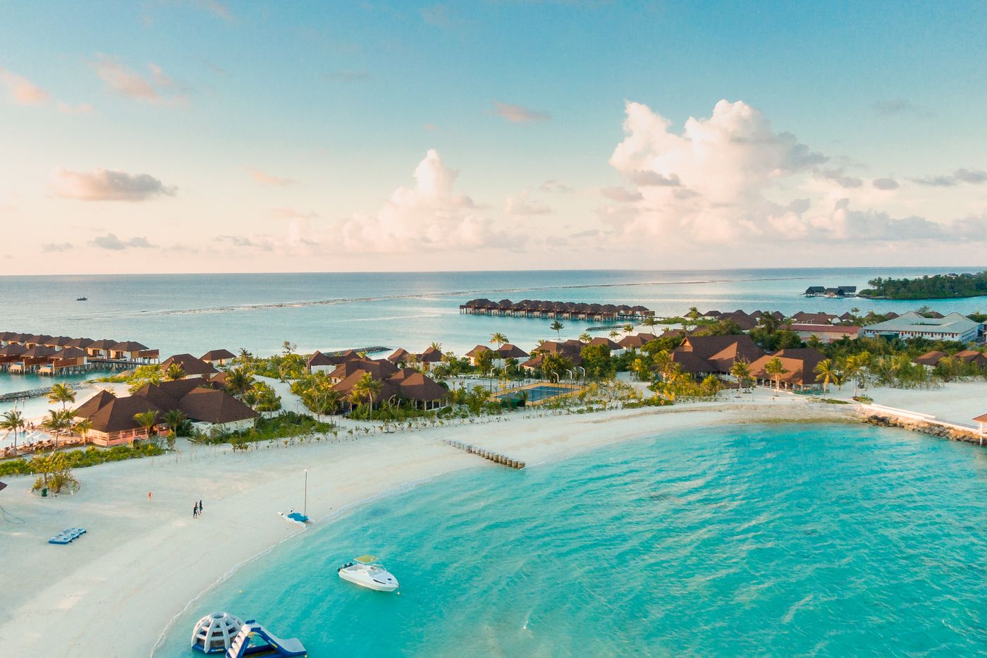 Aerial view of a turquoise private island resort with overwater villas